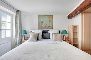 A bedroom with a bed, two bedside tables, a wall-mounted artwork, a wooden wardrobe, and a window with curtains. - Stunning Duplex 1br/4p - Notre-dame Cathedral (Paris)