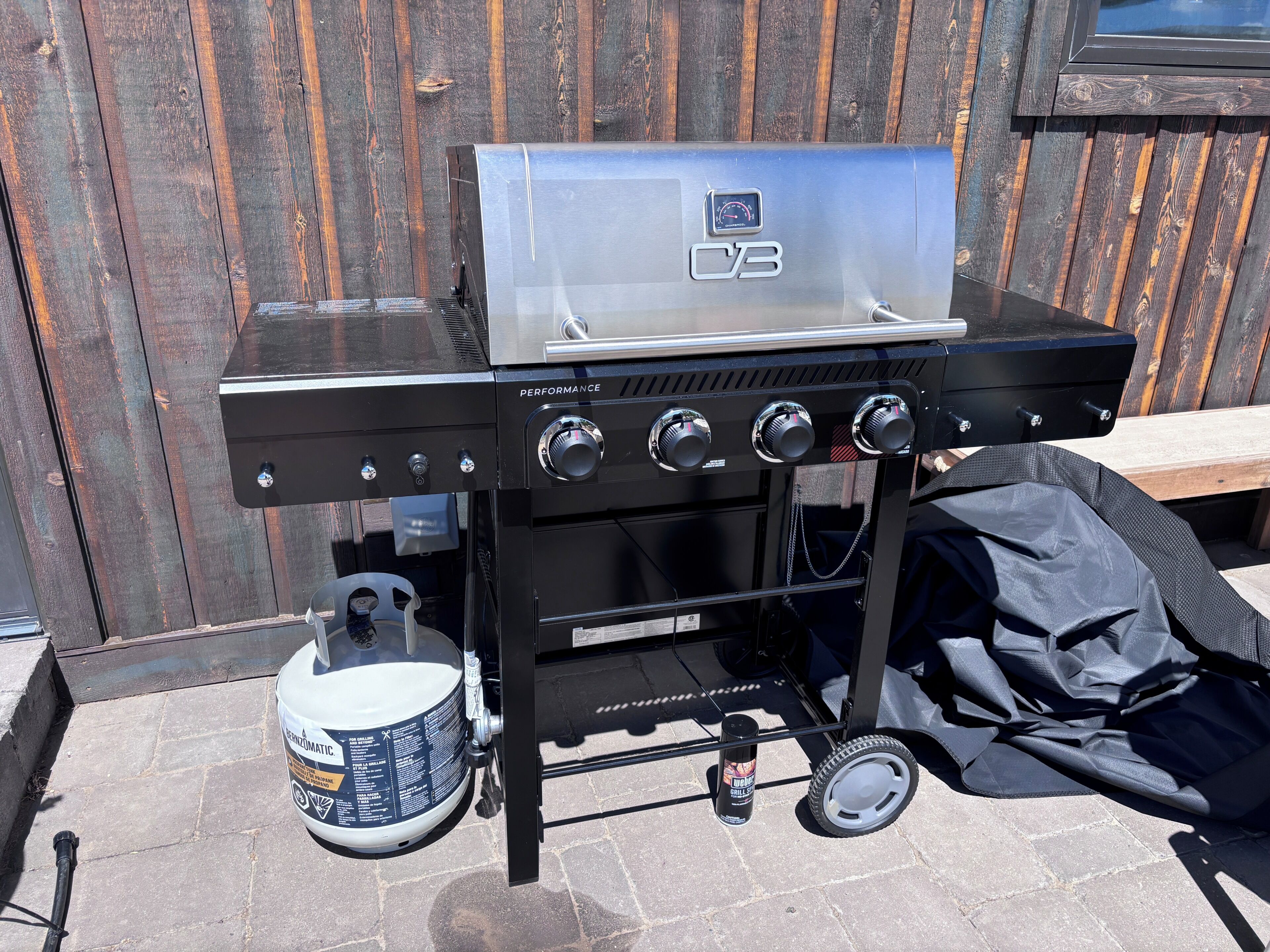 Ein tragbarer Gasgrill mit digitaler Anzeige, mehreren Drehreglern und einer Propangasflasche.