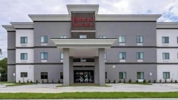 A modern Redwood Inn & Suites building with a symmetrical facade, multiple windows, and a central entrance.