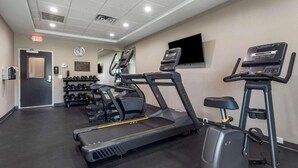 A gym with treadmills, a stationary bike, and dumbbells.