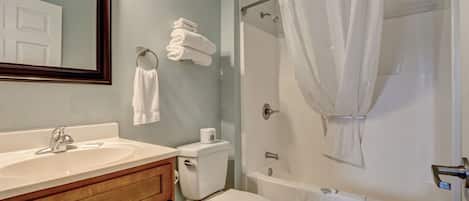 Un baño con lavamanos, inodoro, bañera y cortina de ducha.