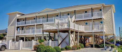 A multi-story hotel with balconies, a covered outdoor area, and a parking lot.