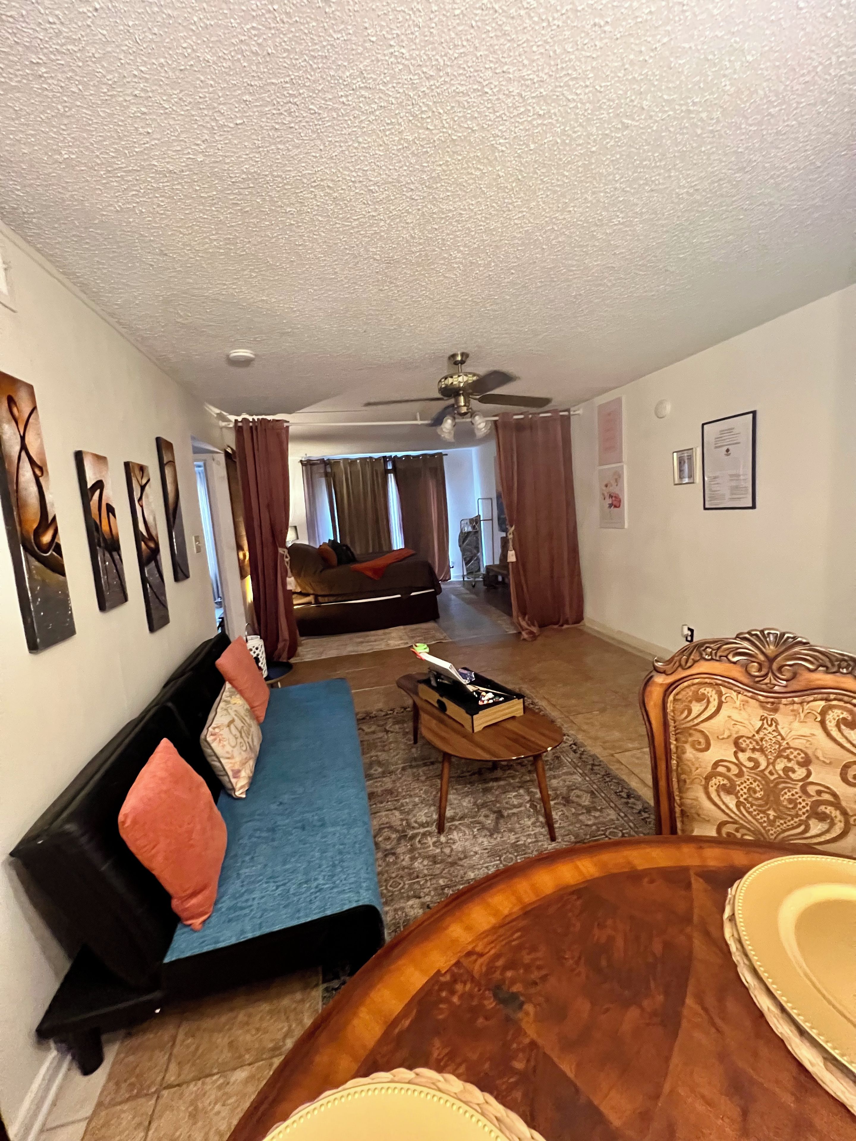 A living room with a sofa, a coffee table, and a dining area with a table and chairs.