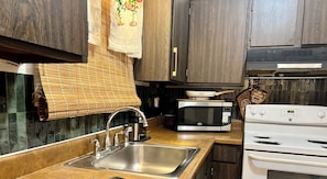 A kitchen with a stainless steel sink, a microwave, and a stove. - Condo • 2 Beds •1 ba near Downtown-Riverwalk, La cantera-Fiesta Texas, Sea World (San Antonio)
