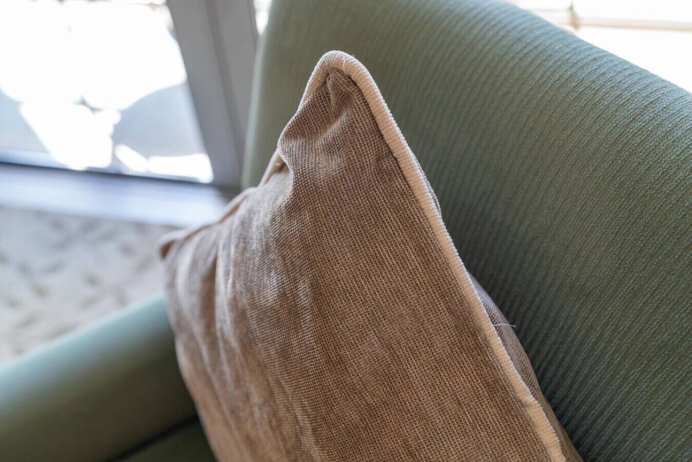 Um sofá verde com uma almofada marrom.