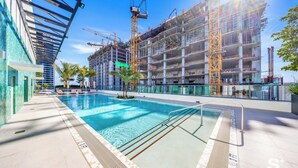 Ein Schwimmbecken mit modernem Design, umgeben von einem Baugebäude, das mit Gerüsten und Kränen ausgestattet ist.