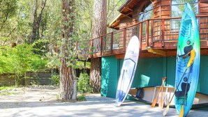Una cabaña de madera con terraza, kayaks y palas.