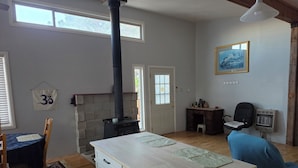 A room with a fireplace, a dining table, a blue chair, a desk, and a chair.