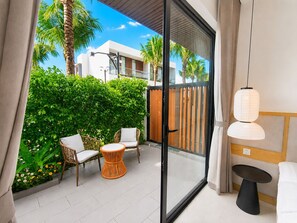 A balcony with wicker chairs, a small round table, and a hanging light fixture. - Kalia Villa (Phu Quoc)