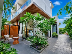 A modern two-story house with a balcony, outdoor seating, and a garden area. - Kalia Villa (Phu Quoc)
