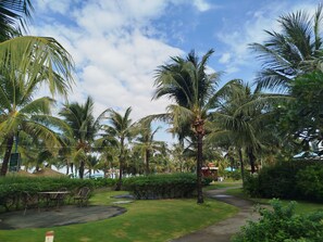 A tropical garden with palm trees, a pathway, and outdoor seating. - Kalia Villa (Phu Quoc)
