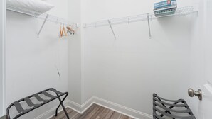 A corner of a room with a white wall, a wooden floor, a metal rack, and a door with a round handle. - Lucky Snapper - Walk to Beach & Tiki Bar, Pets Ok (Carolina Beach)