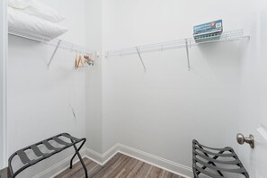 Eine Ecke eines Raumes mit weißer Wand, Holzboden, einem Metallregal und einer Tür mit runder Klinke.