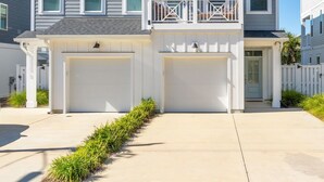 A two-story residential building with a garage, a balcony, and a well-maintained lawn. - Lucky Snapper - Walk to Beach & Tiki Bar, Pets Ok (Carolina Beach)