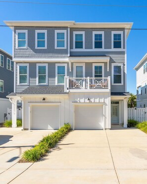 Ein zweistöckiges Wohnhaus mit Garage, Balkon und gepflegtem Rasen.