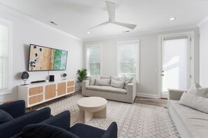 Ein modernes Wohnzimmer mit einem weißen Sofa, einem runden Couchtisch und einem an der Wand montierten Fernseher.