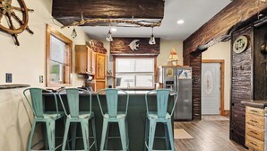 Una cocina con barra, detalles de madera y techo rústico.