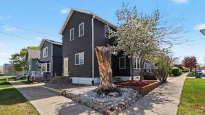 Una casa con jardín delantero, un árbol y una acera.