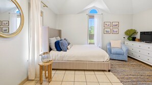 A bedroom with a bed, a chair, a dresser, a mirror, and a window. - Nautigull- A Fisherman's Delight (Apalachicola)