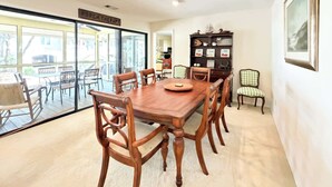 Un comedor con mesa y sillas de madera, una estantería y un cartel que dice 'PORCH THERAPY'.