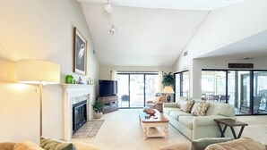 Una sala de estar amplia con chimenea, televisión y un gran ventanal.