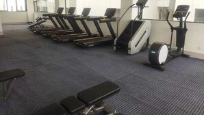 Ein Fitnessraum mit Laufbändern, Crosstrainern und Bänken.