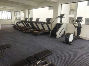 Ein Fitnessraum mit Laufbändern, Crosstrainern und Bänken.
