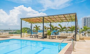 A rooftop pool with a covered seating area, lounge chairs, and a view of the cityscape. - Cartagena Beach Resort By HostPro (Cartagena)