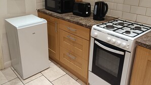 A compact kitchen with a refrigerator, microwave, toaster, coffee maker, and stove.