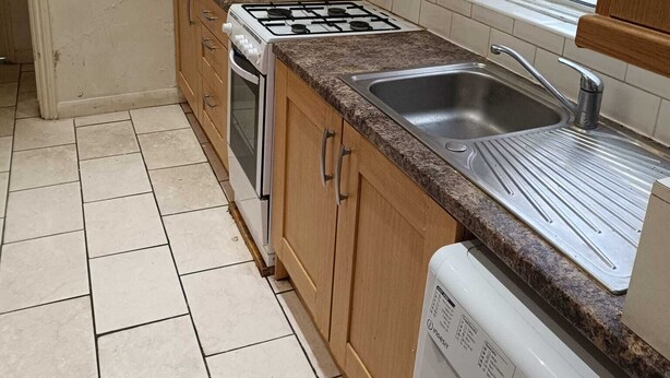 A kitchen with a gas stove, oven, microwave, sink, and washing machine.