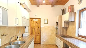 A kitchen with wooden cabinets, a double sink, and a wooden door. - Comfortable House With a Sauna, Close to the Lake (Purda)