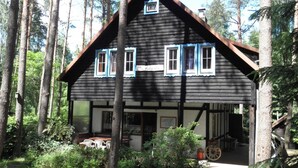 A wooden cabin with a porch, surrounded by trees. - Comfortable House With a Sauna, Close to the Lake (Purda)
