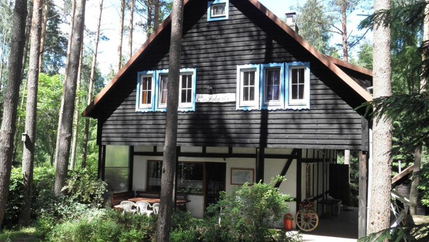 A wooden cabin with a porch, surrounded by trees. - Comfortable House With a Sauna, Close to the Lake (Purda)
