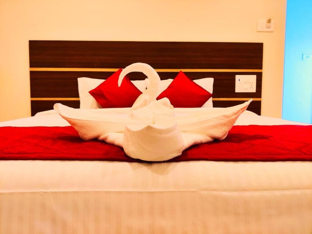 A bed with a red blanket and a swan-shaped pillow arrangement.