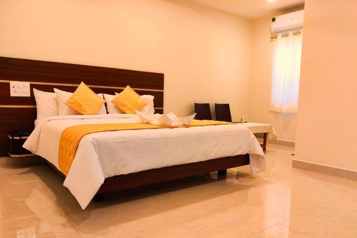 Un letto rifatto con una coperta bianca e gialla, una testiera in legno e un comodino con una lampada.