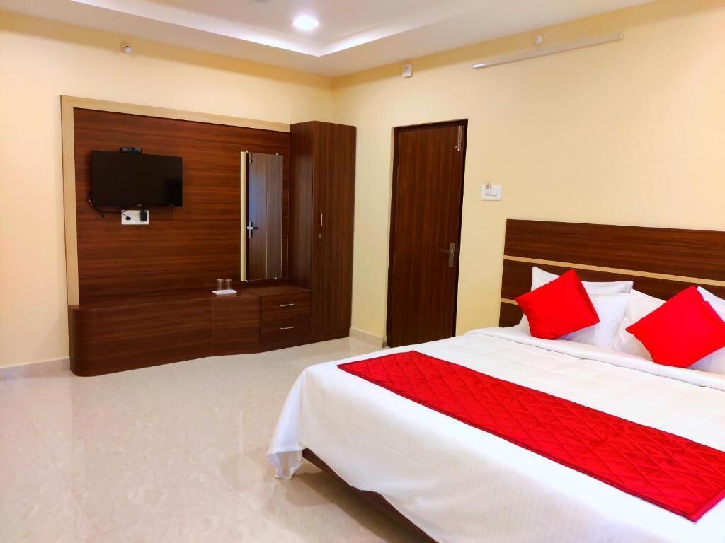 Una habitación de hotel con una cama, televisión montada en la pared, armario y una puerta.