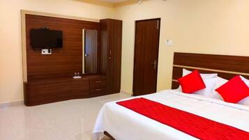 Una habitación de hotel con una cama, televisión montada en la pared, armario y una puerta.