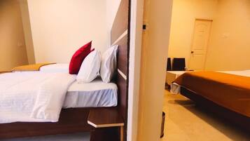 Una habitación de hotel con una cama, una mesita de noche, una silla y una puerta.
