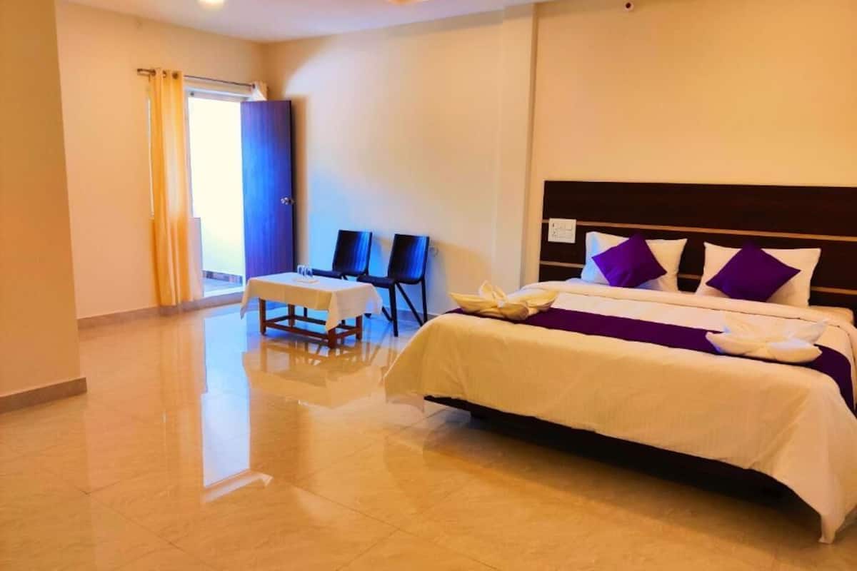 Una camera d'albergo con un letto, un tavolo, sedie e vista sull'esterno.