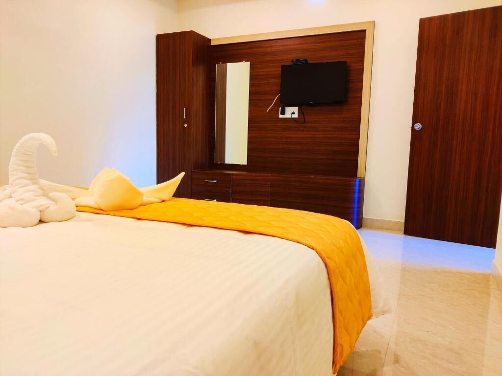 A bedroom with a bed, a TV mounted on the wall, and a wardrobe.
