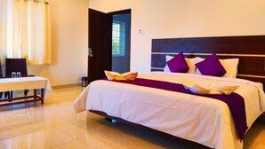A hotel room with a bed, a table, and a window. - THAAI RESIDENCY (Tiruvannamalai)