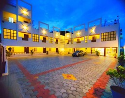 Un hotel de varios pisos con un patio central, piso de baldosas y un automóvil estacionado.