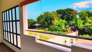 A balcony with a view of greenery and a building in the background. - THAAI RESIDENCY (Tiruvannamalai)