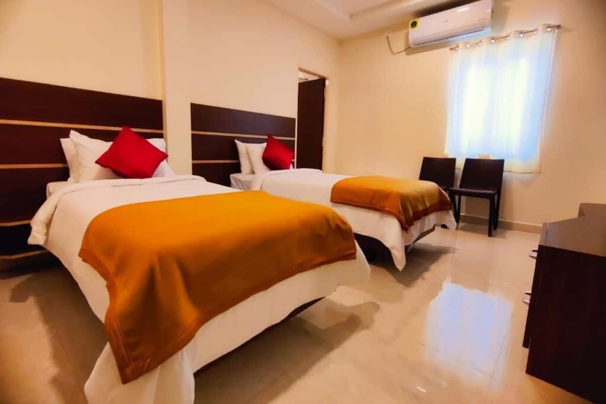 Una camera d'albergo con due letti, una scrivania e un condizionatore.