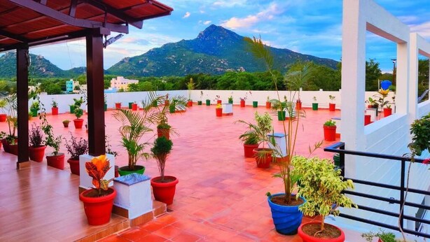 A rooftop terrace with potted plants, a mountain view, and a white structure. - THAAI RESIDENCY (Tiruvannamalai)