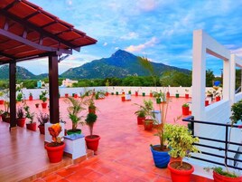 Una terraza en la azotea con plantas en macetas, vistas a la montaña y una estructura blanca.