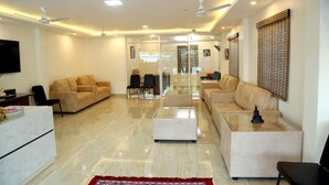 A modern living room with a sofa set, a coffee table, and a TV mounted on the wall. - THAAI RESIDENCY (Tiruvannamalai)