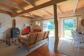 L’intérieur d’un chalet rustique, avec un mur en pierre, des meubles en bois, une cheminée et une vue sur l’extérieur.