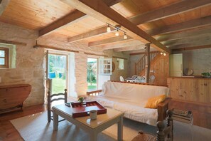 L’intérieur d’un chalet rustique, avec un plafond en bois, un canapé blanc, une table à manger et un coin cuisine.