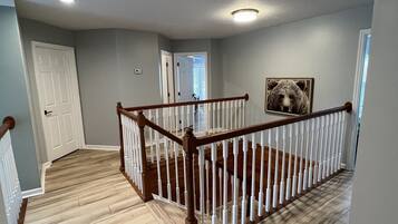 Un hall d’entrée spacieux avec un escalier en bois, une porte blanche et un tableau encadré accroché au mur.